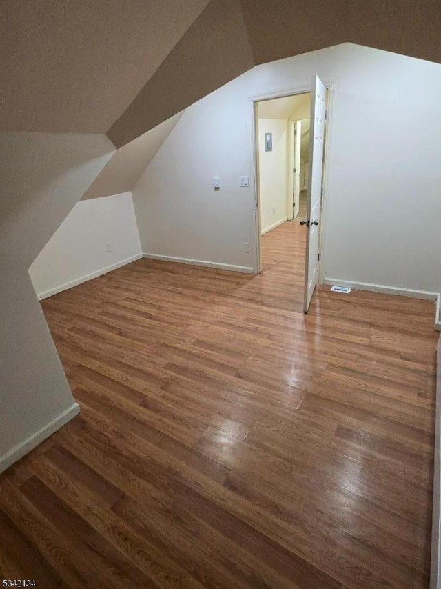 bonus room with visible vents, baseboards, lofted ceiling, and wood finished floors