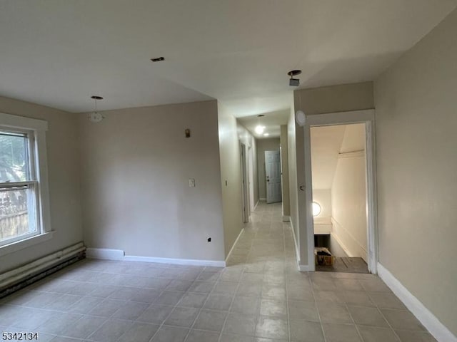 spare room featuring a baseboard heating unit and baseboards