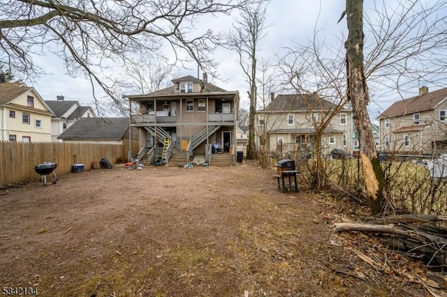 rear view of property featuring stairway, a residential view, and fence