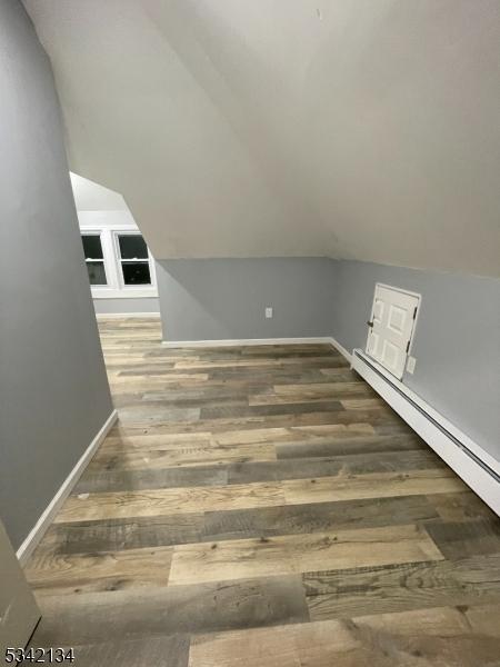 additional living space with baseboards, lofted ceiling, and wood finished floors