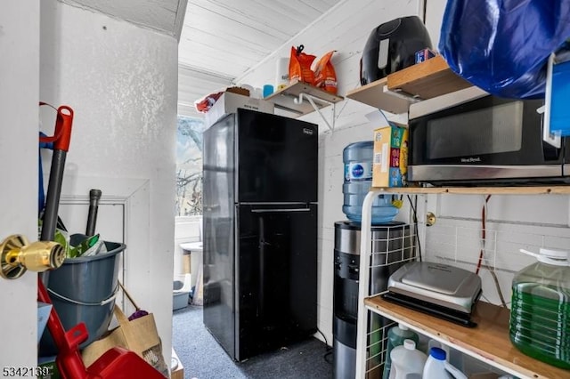 kitchen with stainless steel microwave and freestanding refrigerator