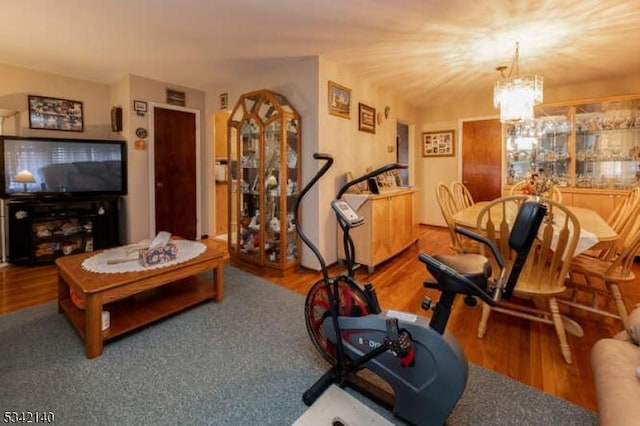 workout room featuring a chandelier and wood finished floors