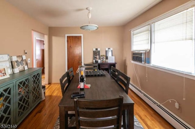 dining area with a baseboard heating unit and wood finished floors