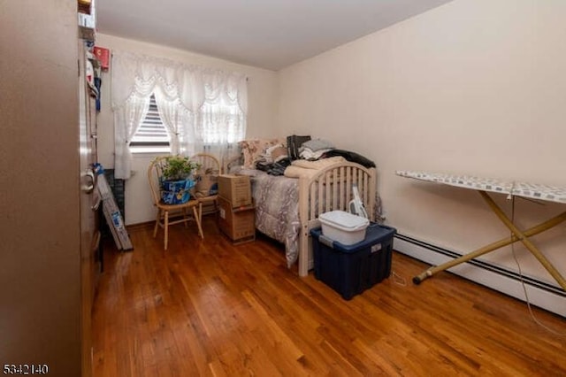 bedroom with baseboard heating and wood finished floors