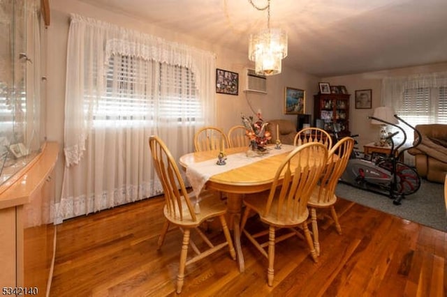 dining space featuring a wall mounted air conditioner, wood finished floors, a wealth of natural light, and an inviting chandelier