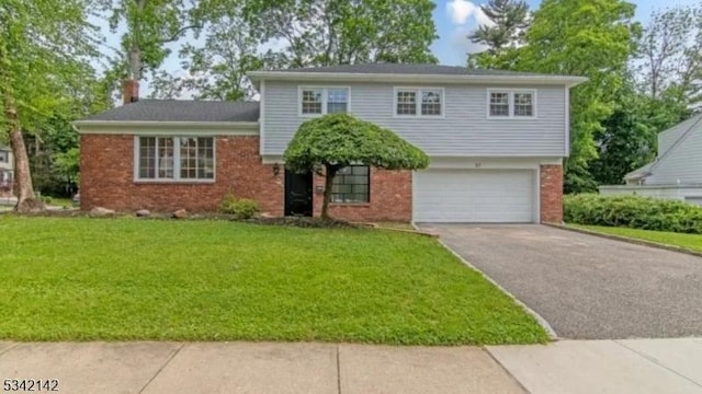 tri-level home featuring a garage, a chimney, aphalt driveway, a front lawn, and brick siding