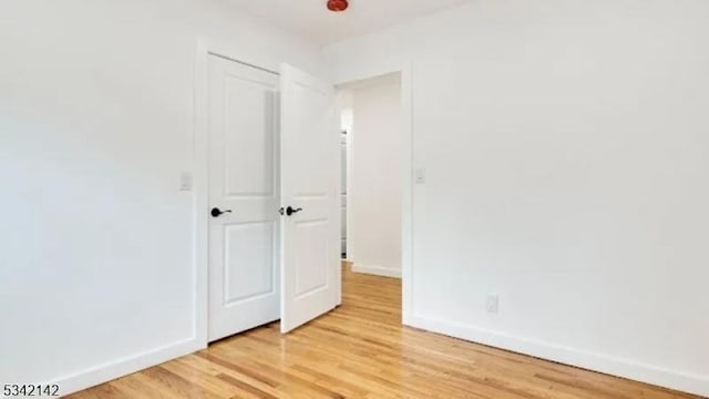 unfurnished bedroom with light wood-style flooring and baseboards