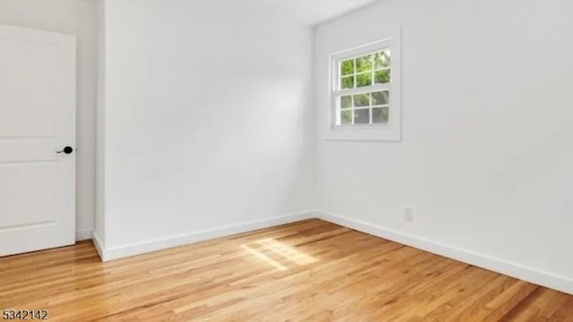 empty room featuring light wood finished floors and baseboards