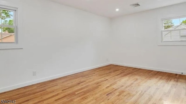 spare room featuring light wood-style floors, recessed lighting, visible vents, and baseboards