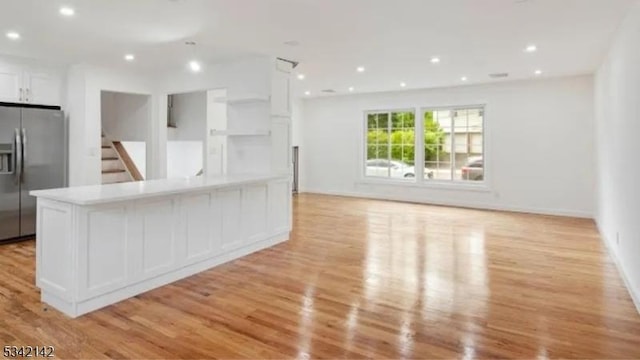 kitchen with light wood finished floors, white cabinetry, open floor plan, and stainless steel fridge with ice dispenser