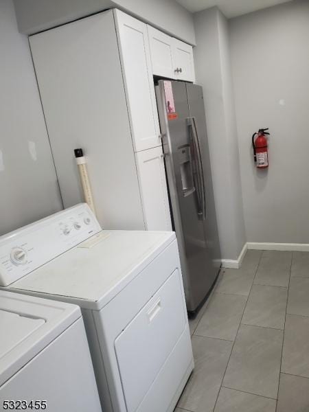 laundry area with cabinet space, baseboards, washer and clothes dryer, and light tile patterned flooring