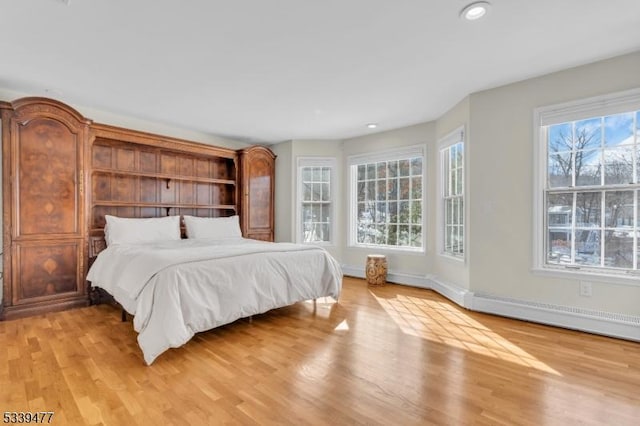 bedroom featuring a baseboard heating unit, recessed lighting, light wood-style flooring, and baseboards