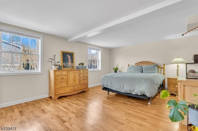 bedroom with light wood-style floors, beam ceiling, and baseboards