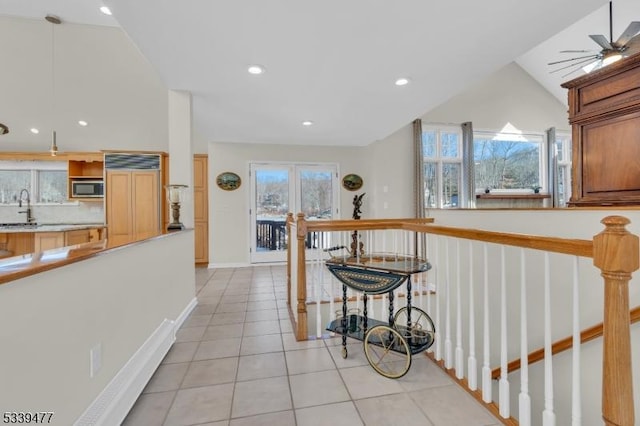 corridor featuring light tile patterned floors, baseboards, an upstairs landing, a sink, and recessed lighting