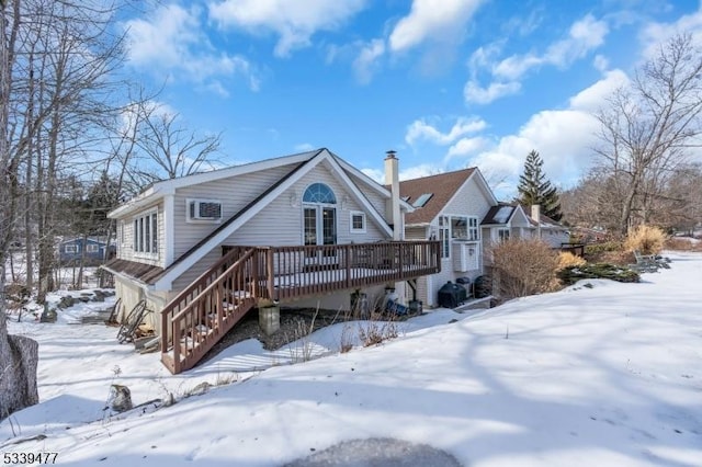 snow covered back of property with stairs and a wooden deck