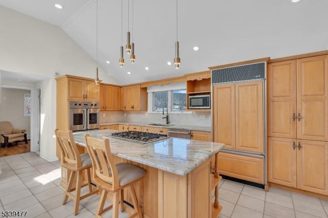 kitchen with light stone counters, a kitchen island, a sink, built in appliances, and a kitchen bar