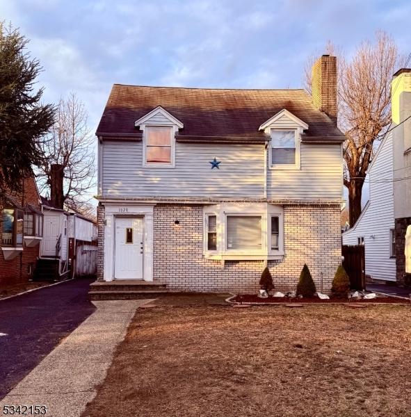 view of front of home featuring brick siding and a chimney