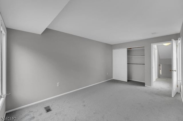 unfurnished bedroom with a closet, carpet flooring, visible vents, and baseboards