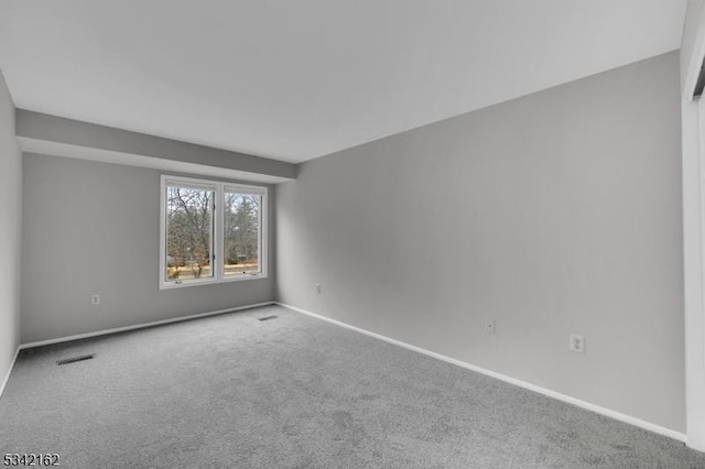 carpeted spare room with visible vents and baseboards