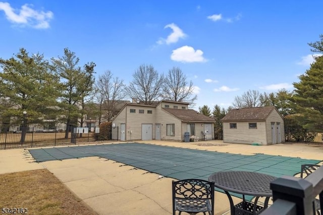 pool featuring a patio area, fence, and an outbuilding