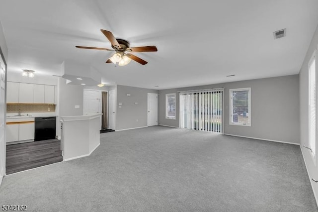 unfurnished living room featuring ceiling fan, carpet flooring, a sink, visible vents, and baseboards