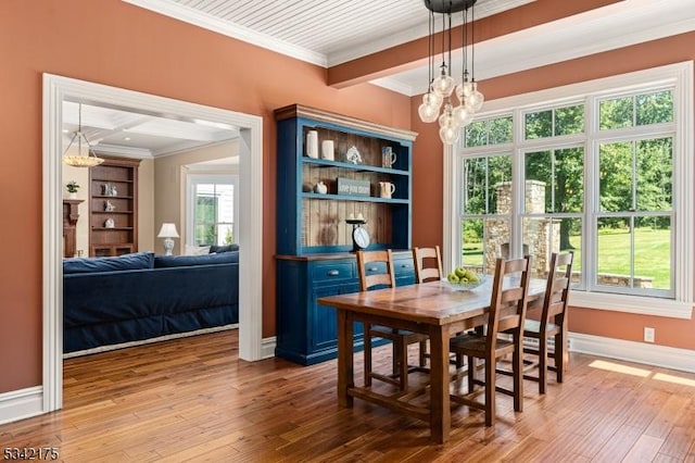 dining space with baseboards, beamed ceiling, wood finished floors, crown molding, and a notable chandelier