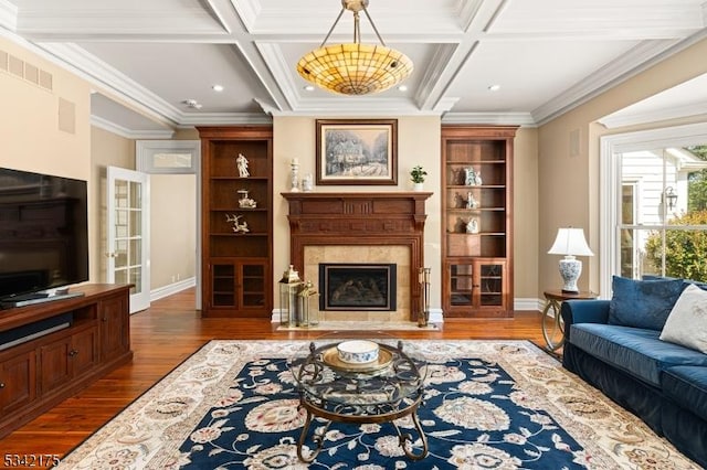 living room featuring visible vents, coffered ceiling, a fireplace with flush hearth, wood finished floors, and crown molding