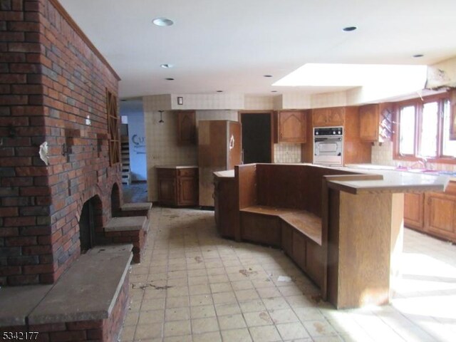 kitchen with recessed lighting, a brick fireplace, freestanding refrigerator, and a kitchen island