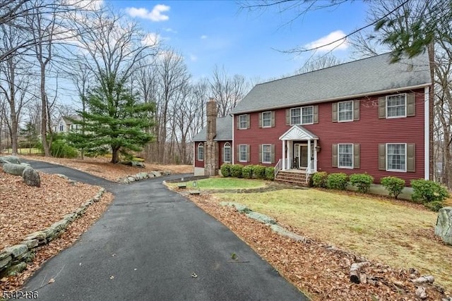 view of front facade with driveway and a chimney