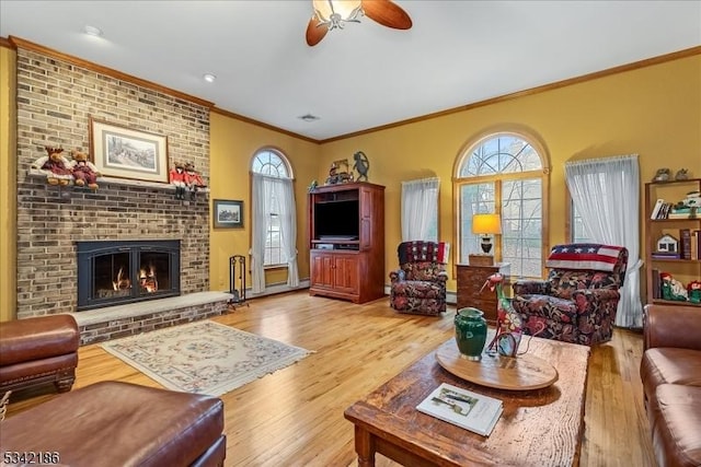 living area featuring crown molding, a fireplace, visible vents, a ceiling fan, and wood finished floors