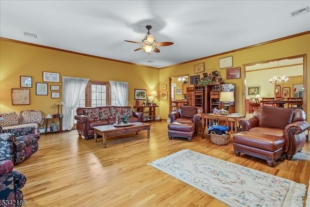 living area featuring ornamental molding, ceiling fan with notable chandelier, visible vents, and wood finished floors