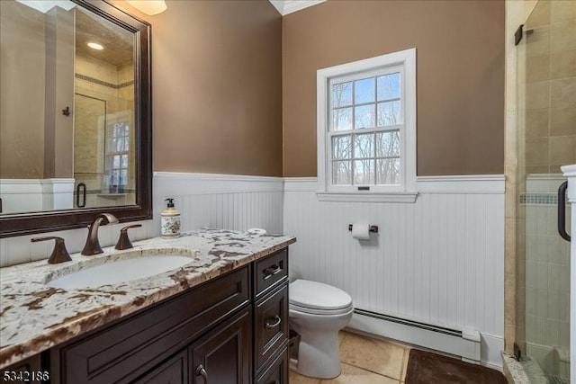 bathroom with a baseboard heating unit, a stall shower, wainscoting, and tile patterned floors