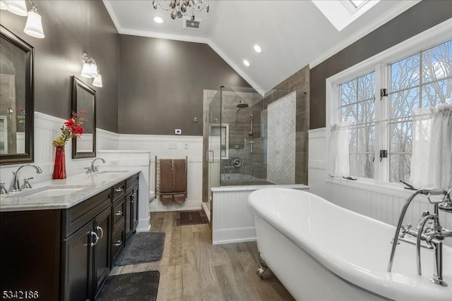 full bathroom with a wainscoted wall, lofted ceiling with skylight, and a sink