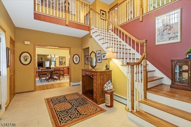 stairway featuring a chandelier, a baseboard radiator, a baseboard heating unit, a high ceiling, and tile patterned floors