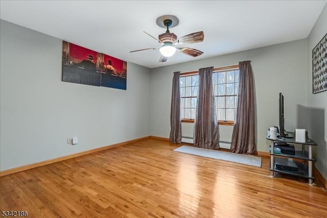 interior space featuring a ceiling fan, baseboards, and wood finished floors