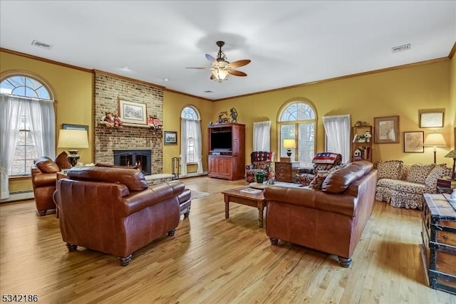 living room featuring ornamental molding, light wood finished floors, a fireplace, and visible vents