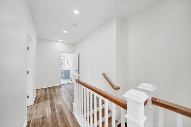 hall with recessed lighting, light wood-style flooring, baseboards, and an upstairs landing