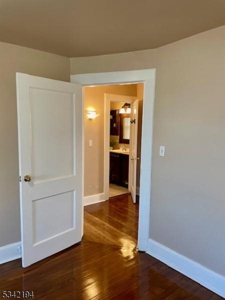 empty room with a sink, baseboards, and wood finished floors