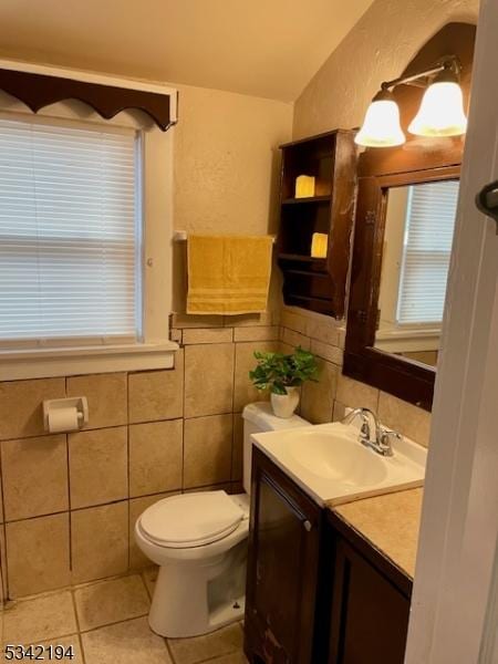 half bathroom with toilet, tile walls, vanity, and tile patterned flooring