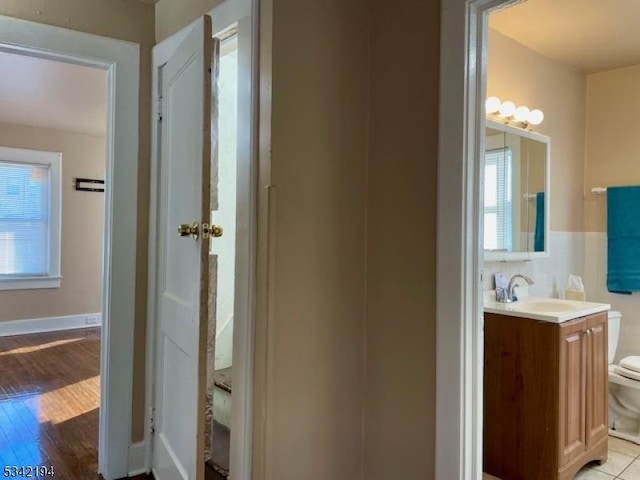 bathroom with toilet, wood finished floors, and vanity