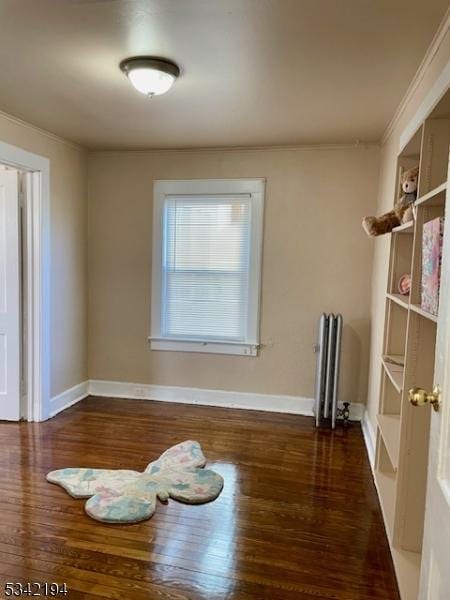 spare room with baseboards, wood finished floors, and crown molding