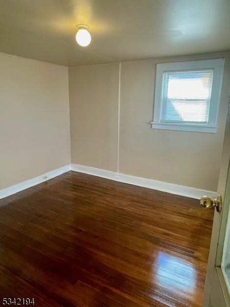 spare room with baseboards and wood finished floors