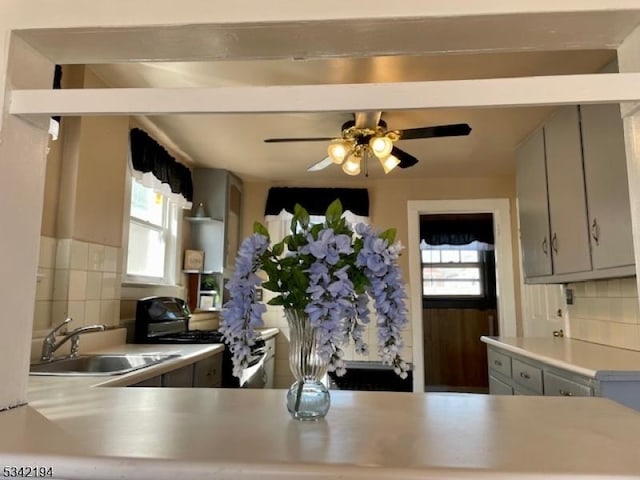 kitchen featuring a sink, tasteful backsplash, a healthy amount of sunlight, and black range with gas cooktop