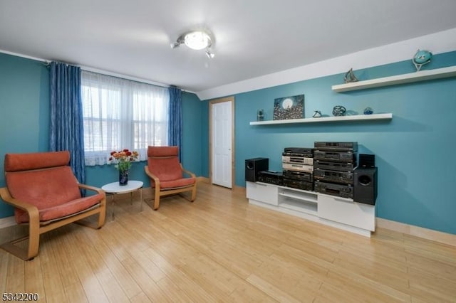 sitting room with baseboards, vaulted ceiling, and wood finished floors