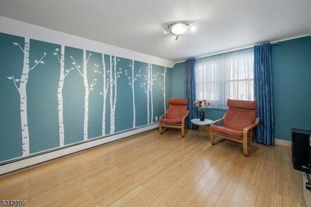 living area featuring a baseboard heating unit, wood finished floors, and baseboards