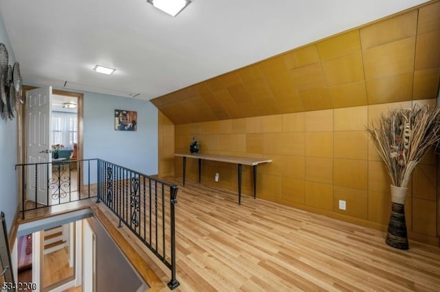 hall with vaulted ceiling, wood finished floors, and an upstairs landing