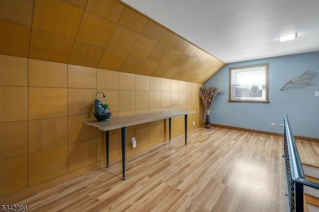 bonus room featuring lofted ceiling, light wood-style floors, and baseboards