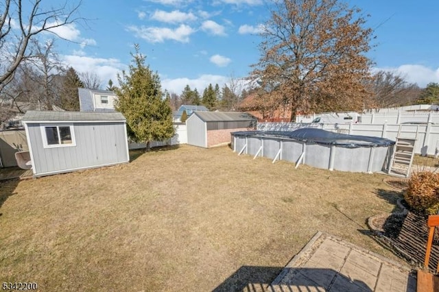 view of yard with an outbuilding, a covered pool, a fenced backyard, and a storage unit