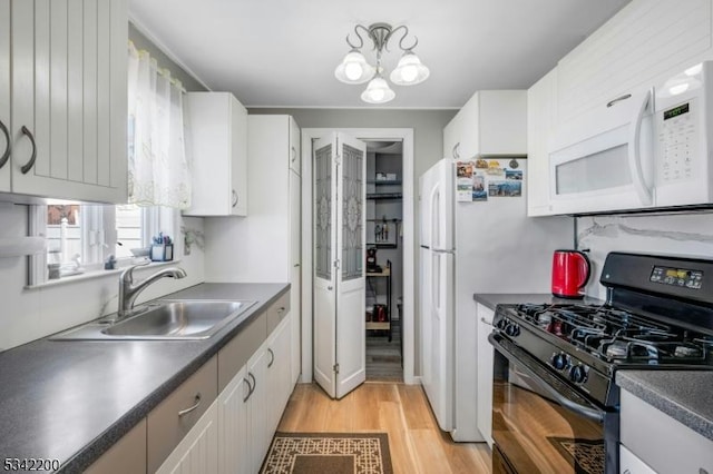 kitchen with dark countertops, white microwave, light wood-type flooring, black gas stove, and a sink