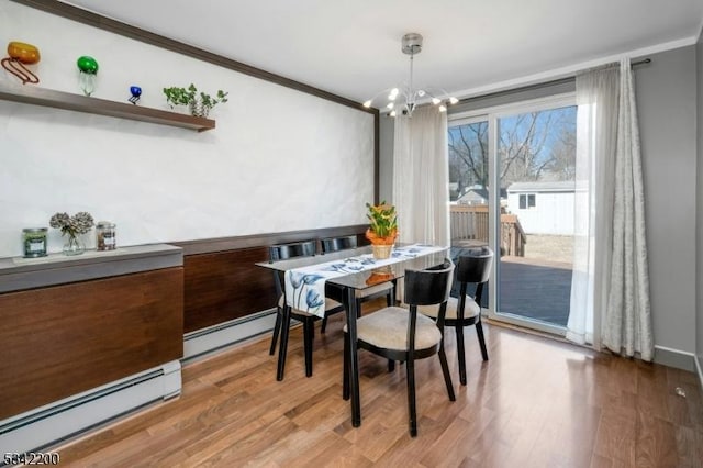 dining room featuring light wood-style floors, a baseboard radiator, crown molding, and a notable chandelier